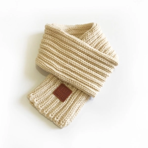 Beige ribbed knit scarf for women with brown leather label in a folded minimalist style