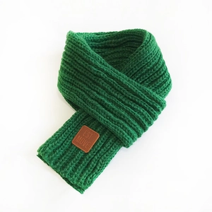 Green chunky knit scarf with premium brown leather label detail on white background