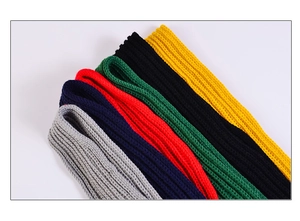 Close-up of neatly stacked knitted children's scarves in multiple vibrant colors