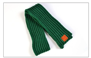 Detail of dark green ribbed knit scarf featuring a brown leather patch with text