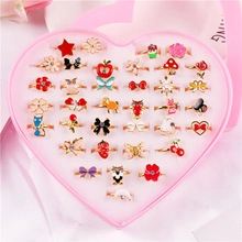 Close-up of 36 adjustable metal cartoon rings for girls in a pink heart gift box