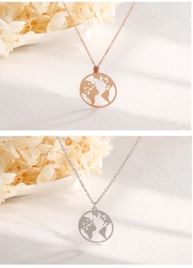 Detailansicht der Weltkarten-Halsketten in Roségold und Silber auf weichem Stoff