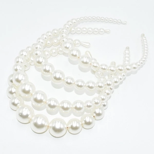 Detail view of a three-piece set of elegant white pearl headbands with golden metal base