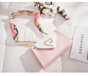 Detailed top view of pink and white crossbody bag with gold heart clasp and floral scarf