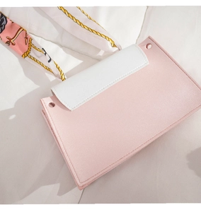 Detail of a pink faux leather handbag with a white flap and decorative silk scarf handle