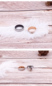 Close-up of heart-shaped diamond couple rings on a wooden background with feathers