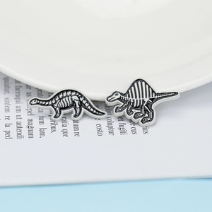 Detail of dinosaur skeleton enamel pins featuring brontosaurus and spinosaurus designs