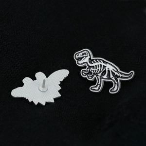 Macro view of T-Rex skeleton enamel pin showing intricate bone detail and metal backing