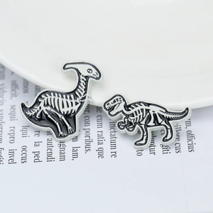 Close-up of enamel dinosaur skeleton pins on a white plate with aesthetic background