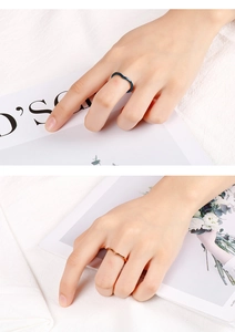 Detailed view of wave V-shaped rings in blue and rose gold finish on a fabric background