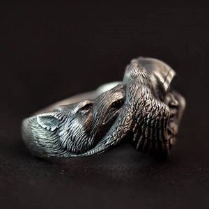 Macro side view of retro wolf and eagle feather carvings on an antique silver ring