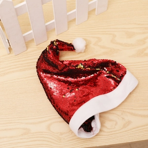 Close-up of red reversible sequin Christmas hat with white plush trim on wood