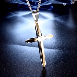 Macro shot of silver and gold two-tone twisted cross pendant on dark textured surface