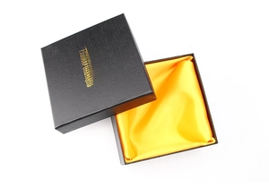 Detail of black leather gift box with gold logo and yellow satin lining for belts
