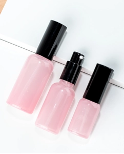 Three pink glass spray and lotion bottles with black pumps for travel storage