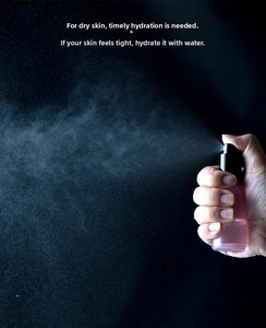 Detailed view of pink spray bottle with black fine mist nozzle releasing water droplets