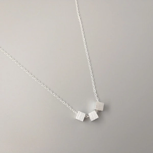 Detail of 925 sterling silver snake chain necklace featuring three minimalist cubes