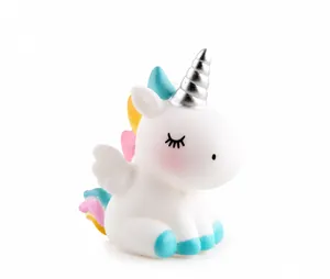 Gros plan d'une licorne blanche pour gâteau avec corne argentée et ailes colorées