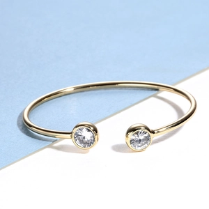 Elegant gold open bangle with two large round white cubic zirconia stones in bezel setting