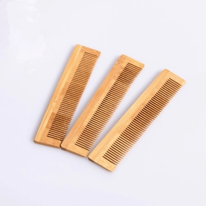 Detailed close-up of three hotel disposable fine-tooth bamboo hair combs with natural wood grain