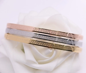 Detail of three-color Greek Key pattern bangles on a white flower in gold, rose gold and silver