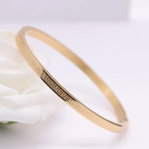 Close-up of gold Greek meander pattern bangle nestled in elegant white roses