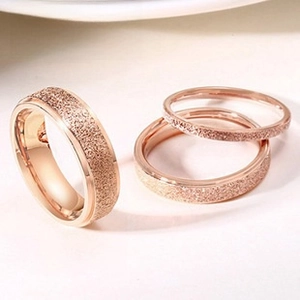 Close-up of three rose gold titanium steel rings with textured matte finish and engraving