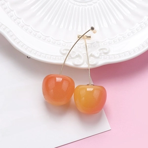 Sweet orange cherry drop earrings with gold hooks on a decorative white porcelain plate