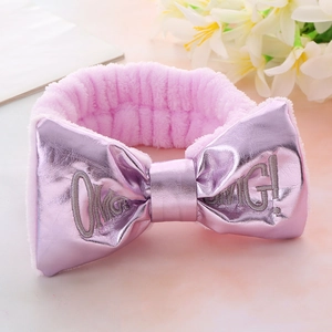Detail of pink plush headband with large OMG! bow and glossy metallic fabric accents