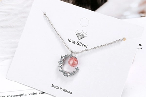 Detailed view of silver moon pendant with red strawberry crystal and zircon accents