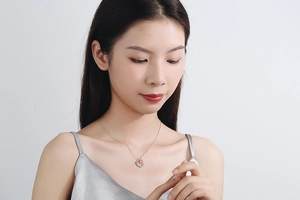 Detail of a crescent moon necklace with pink strawberry crystal on model neck