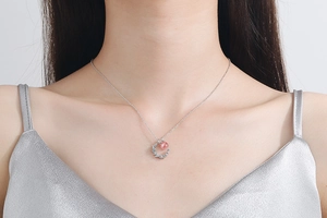 Detail of moon-shaped silver necklace with strawberry crystal on woman's neck