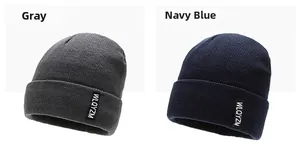 Detail view of grey and navy blue ribbed knit beanies with decorative woven labels