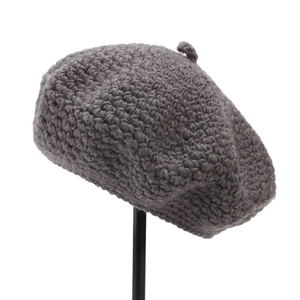 Detail of dark grey hand-crocheted wool beret showing thick knitted texture and top stem