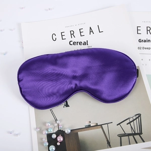 Detailed view of glossy purple silk sleep mask on magazine with pearl accents