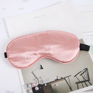 Detail of pink silk sleep mask showing smooth texture and adjustable black elastic strap