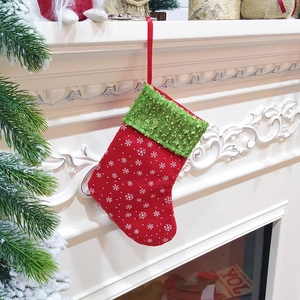 Red Christmas stocking with green cuff and sequins hanging on a white fireplace