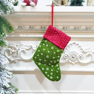 Green Christmas stocking with white snowflake patterns hanging on a fireplace mantel