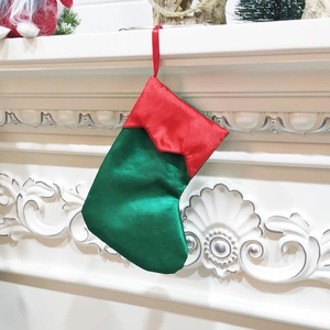 7-inch green and red satin Christmas elf stocking hung on a white classic fireplace
