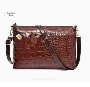 Detailed macro view of the glossy dark brown crocodile texture and gold metal buckle
