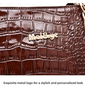 Close-up of brown crocodile texture handbag with golden metal logo decoration