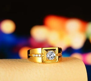 Macro shot of gold plated men's wedding ring with central round diamond and side stones