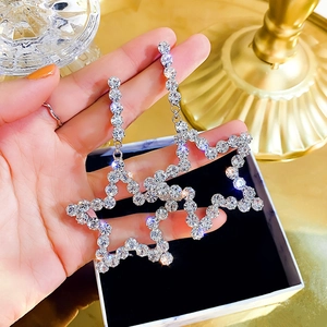 Close-up of sparkling oversized star earrings with crystals and silver needle studs