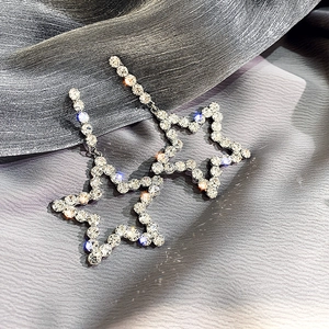 Macro shot of silver star drop earrings with sparkling rhinestones on grey silk texture