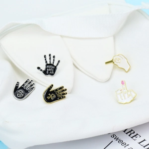 Detail of occult hand enamel pins on white canvas showing rock and mystical symbols