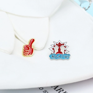 Detail of red thumbs up and High Five enamel pins on soft white fabric background