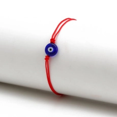 Close-up of red braided rope bracelet featuring a classic blue evil eye glass bead detail