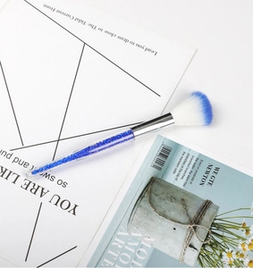 Macro view of a blue and white fan makeup brush with a crystal-filled handle