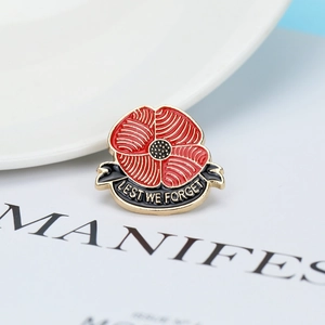 Detailed close-up of a red poppy enamel brooch with Lest We Forget text and golden edges