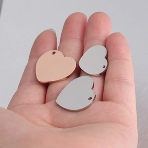 Polished stainless steel heart pendants in silver and rose gold held in hand